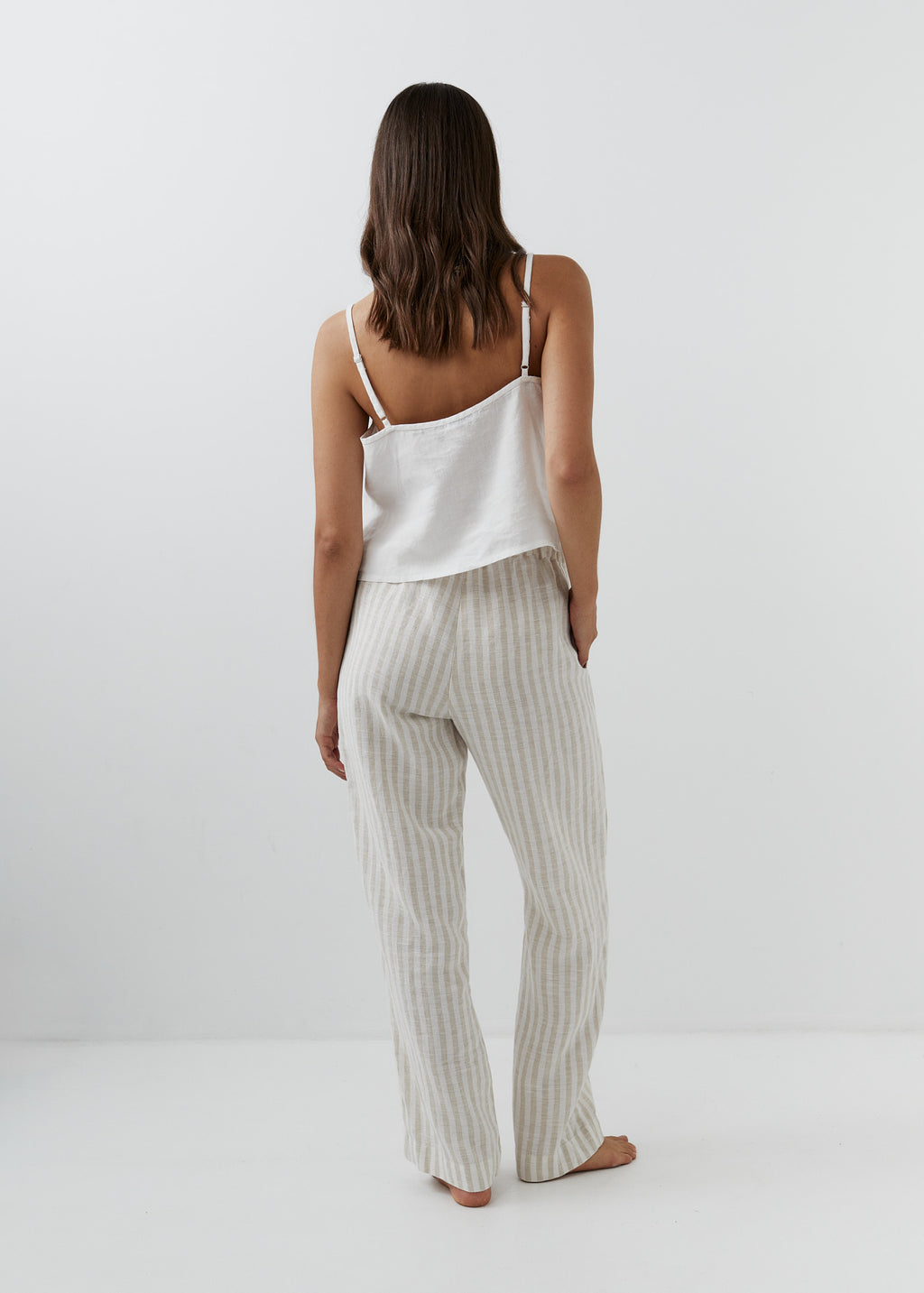 Back view of high-waisted striped linen trousers in beige and white.