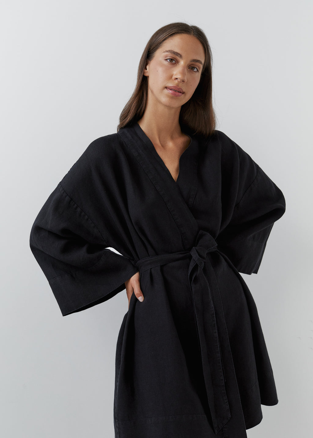 A woman modeling a relaxed short black linen robe with wide long sleeves and a waist tie.