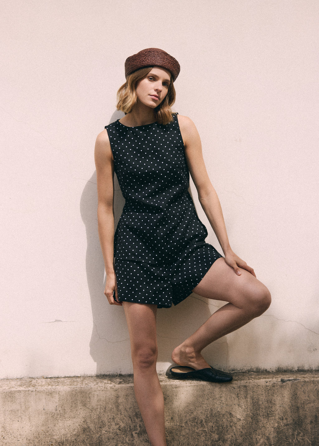 A woman wearing a black and white polka dot linen tie top with matching shorts.