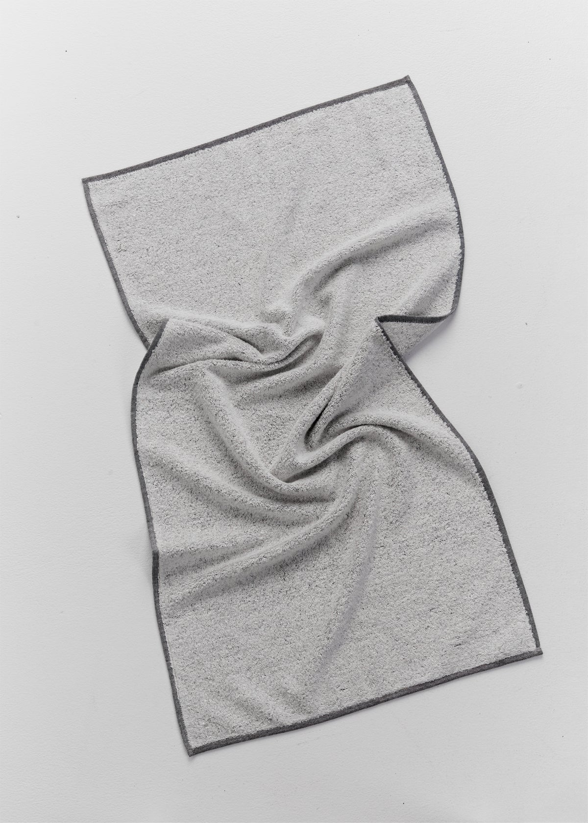 Grey terry towel made with 100% linen loops and a 100% cotton base, loosely draped on a white surface with contrasting dark grey edging.