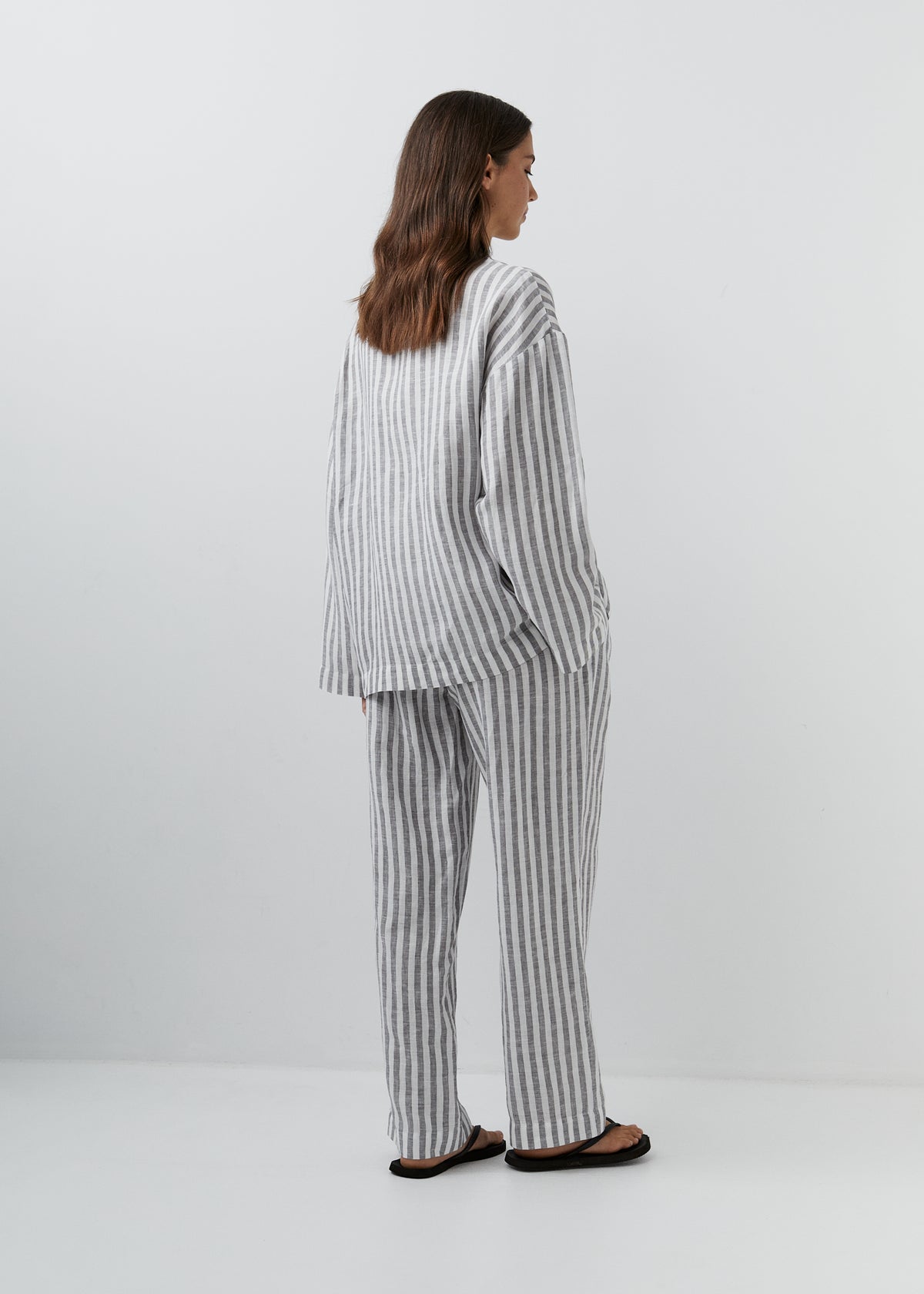 Gray and white striped linen trousers with a relaxed straight-leg silhouette.