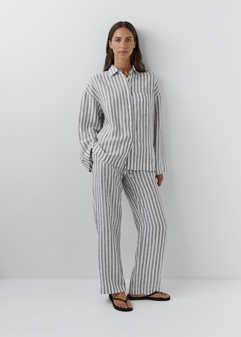 Woman wearing relaxed European linen pants with a matching striped linen shirt.