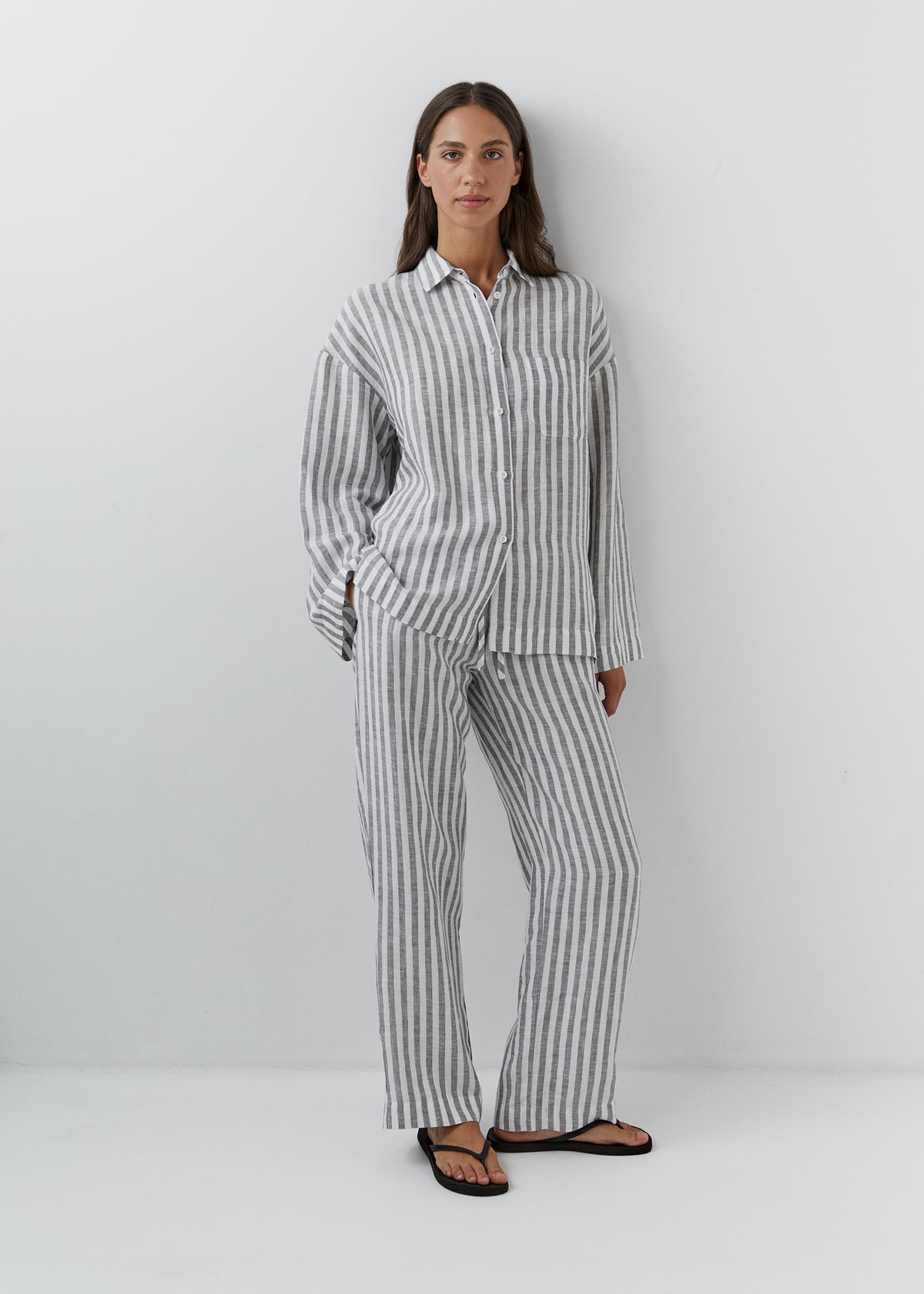 Woman wearing relaxed European linen pants with a matching striped linen shirt.