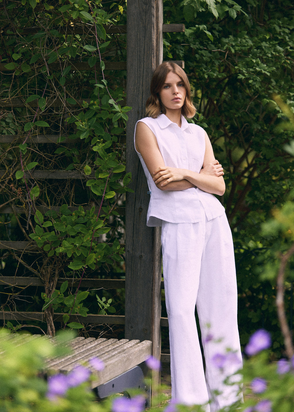 A woman wearing white wide-leg linen trousers with a matching sleeveless linen top outdoors.