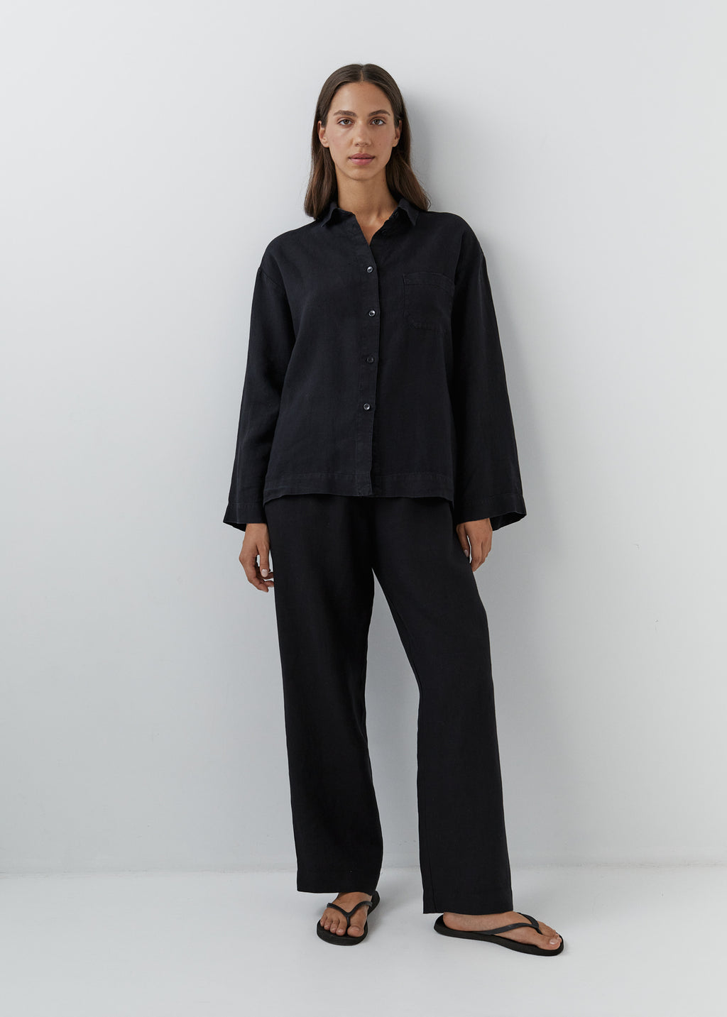 Woman wearing black linen pants with a matching button-down linen shirt.