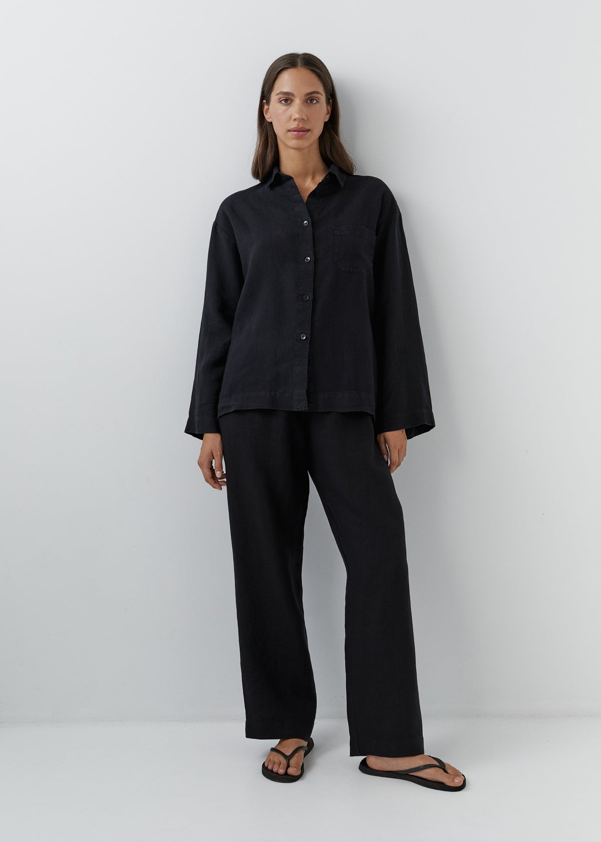 Woman wearing black linen pants with a matching button-down linen shirt.