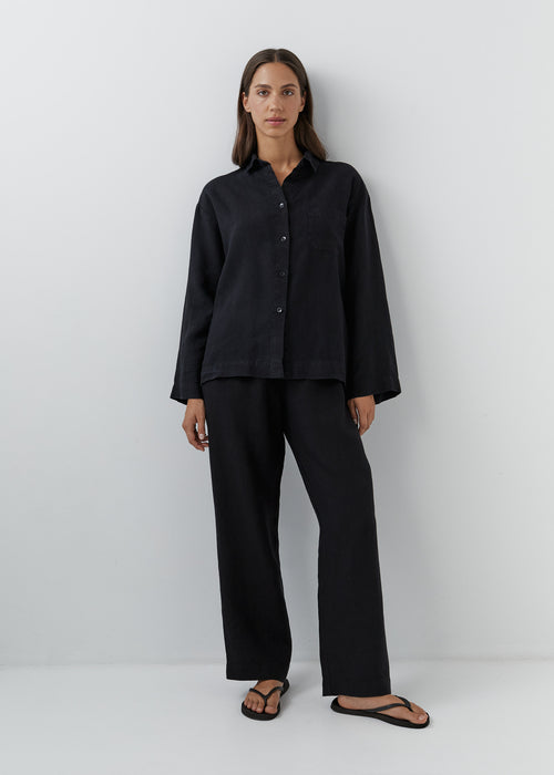 Woman wearing black linen pants with a matching button-down linen shirt.