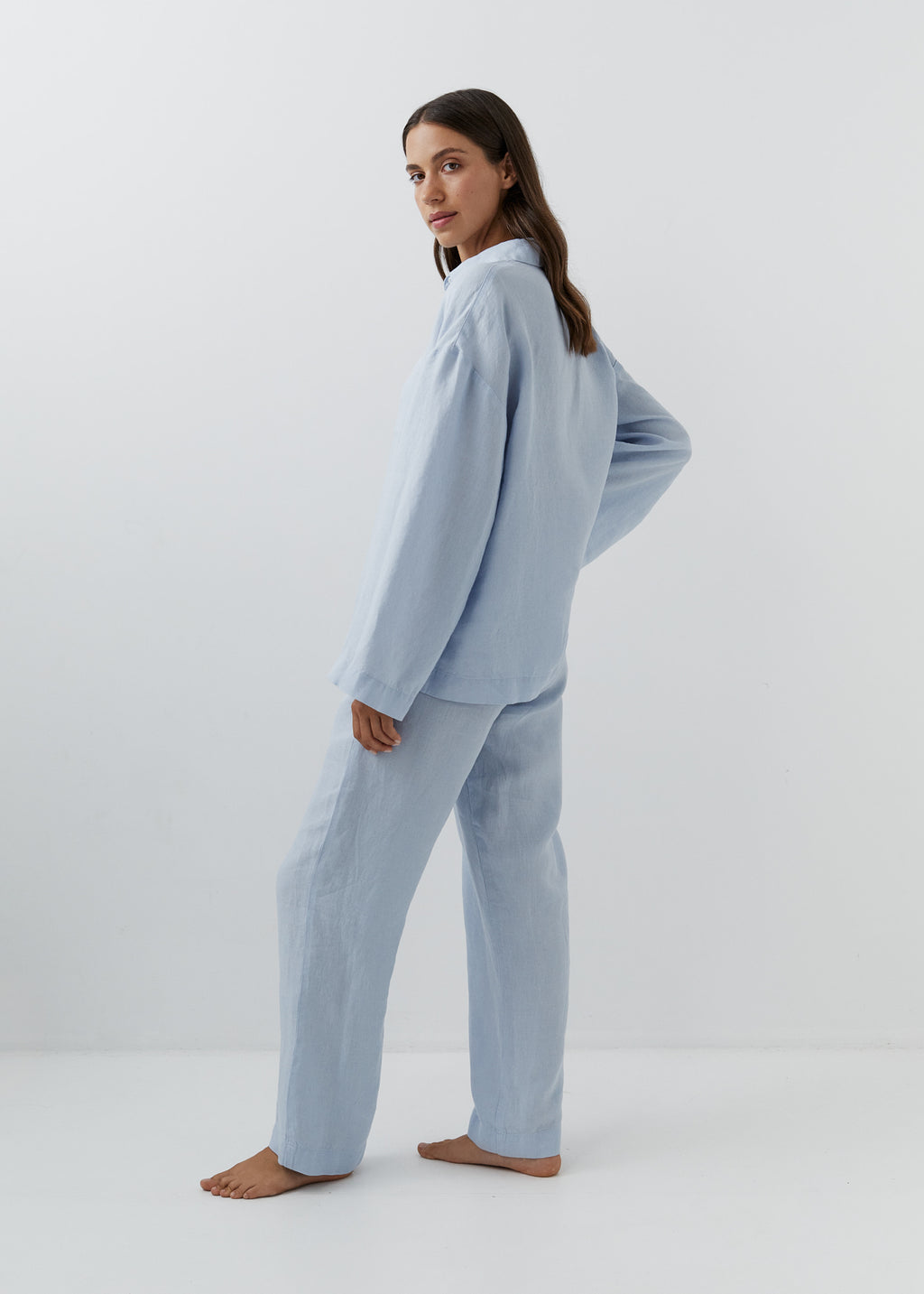 Woman wearing high-waisted blue linen trousers with a matching shirt.