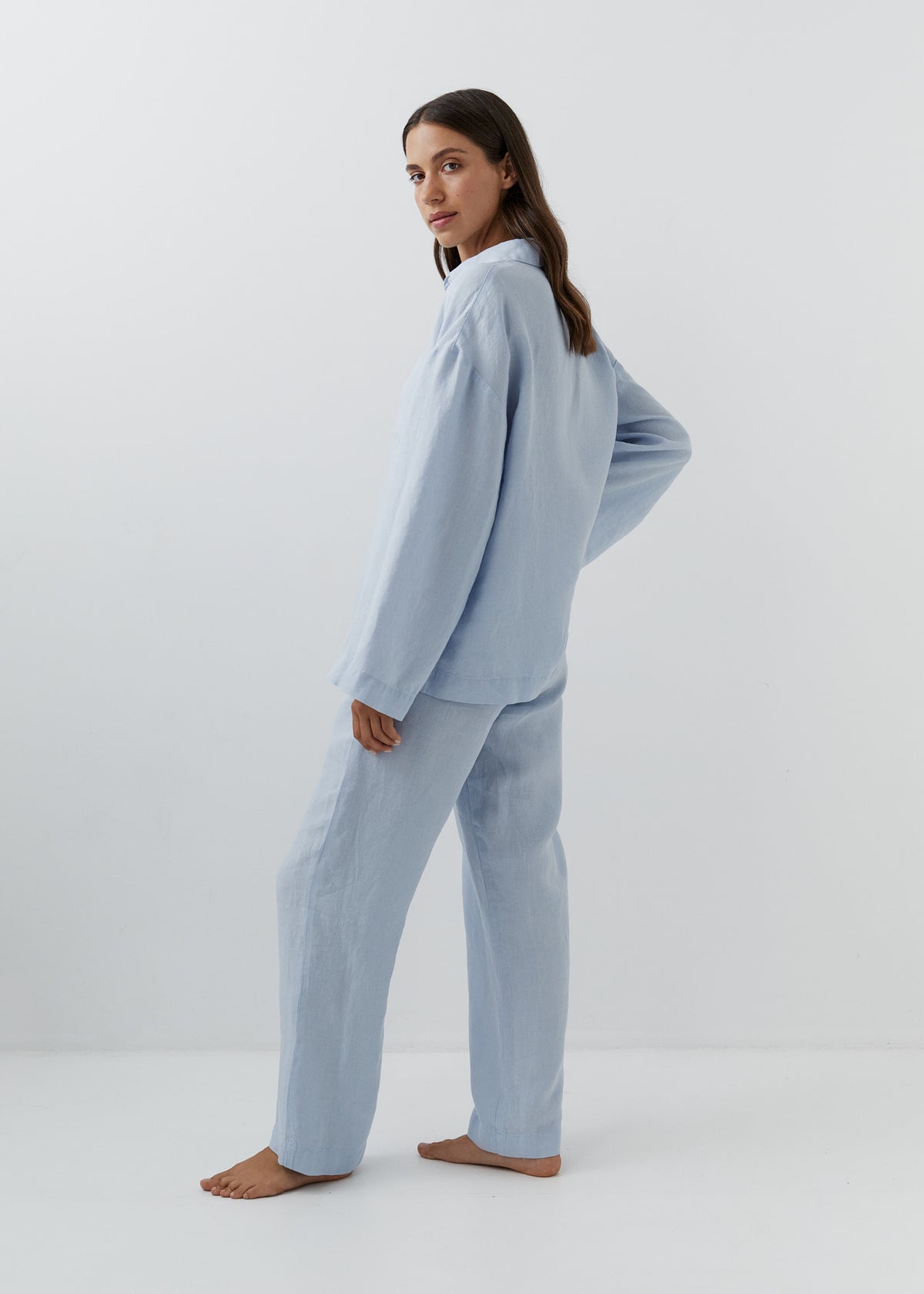 Woman wearing high-waisted blue linen trousers with a matching shirt.