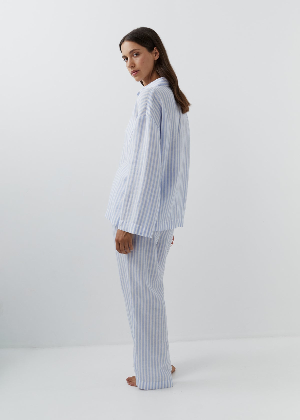 Woman wearing blue striped trousers with a matching linen button-down shirt.
