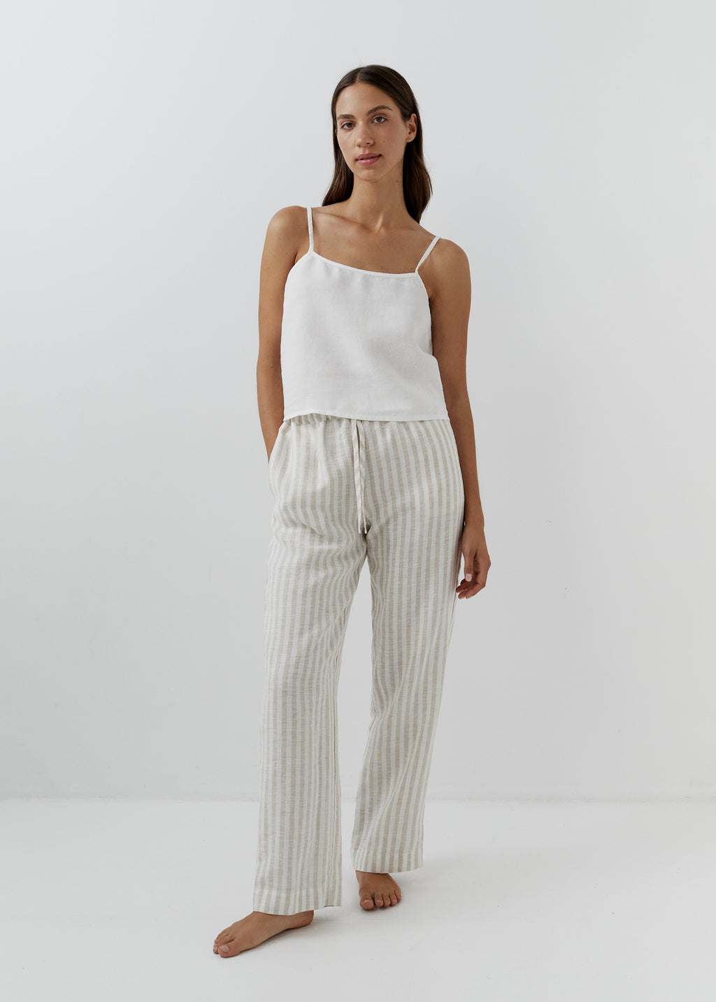 Woman wearing beige and white striped linen pants with a white camisole.