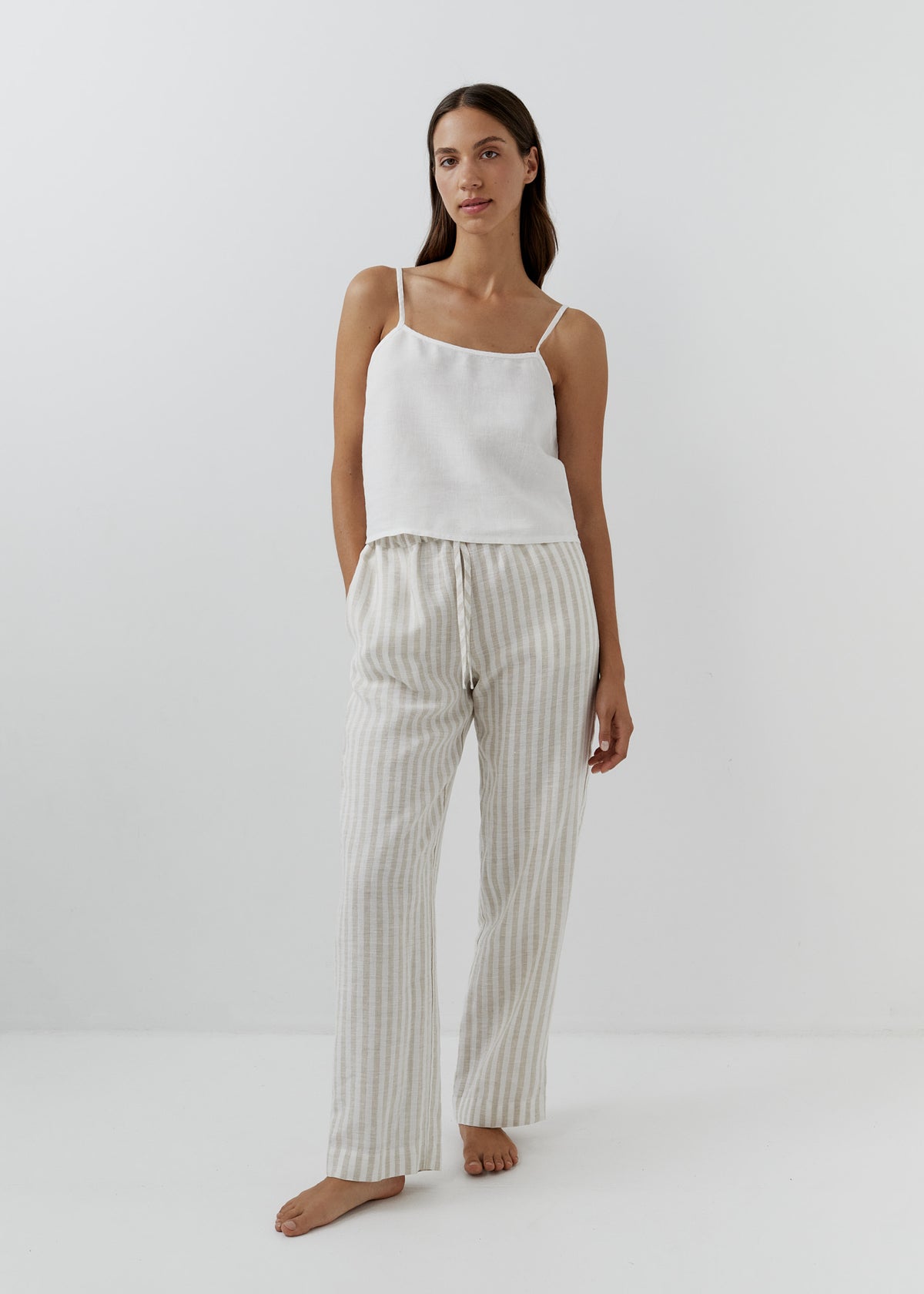 Woman wearing beige and white striped linen pants with a white camisole.