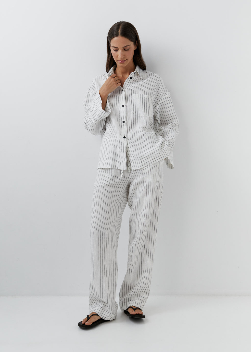 Woman wearing black and white striped linen pants with a matching shirt.