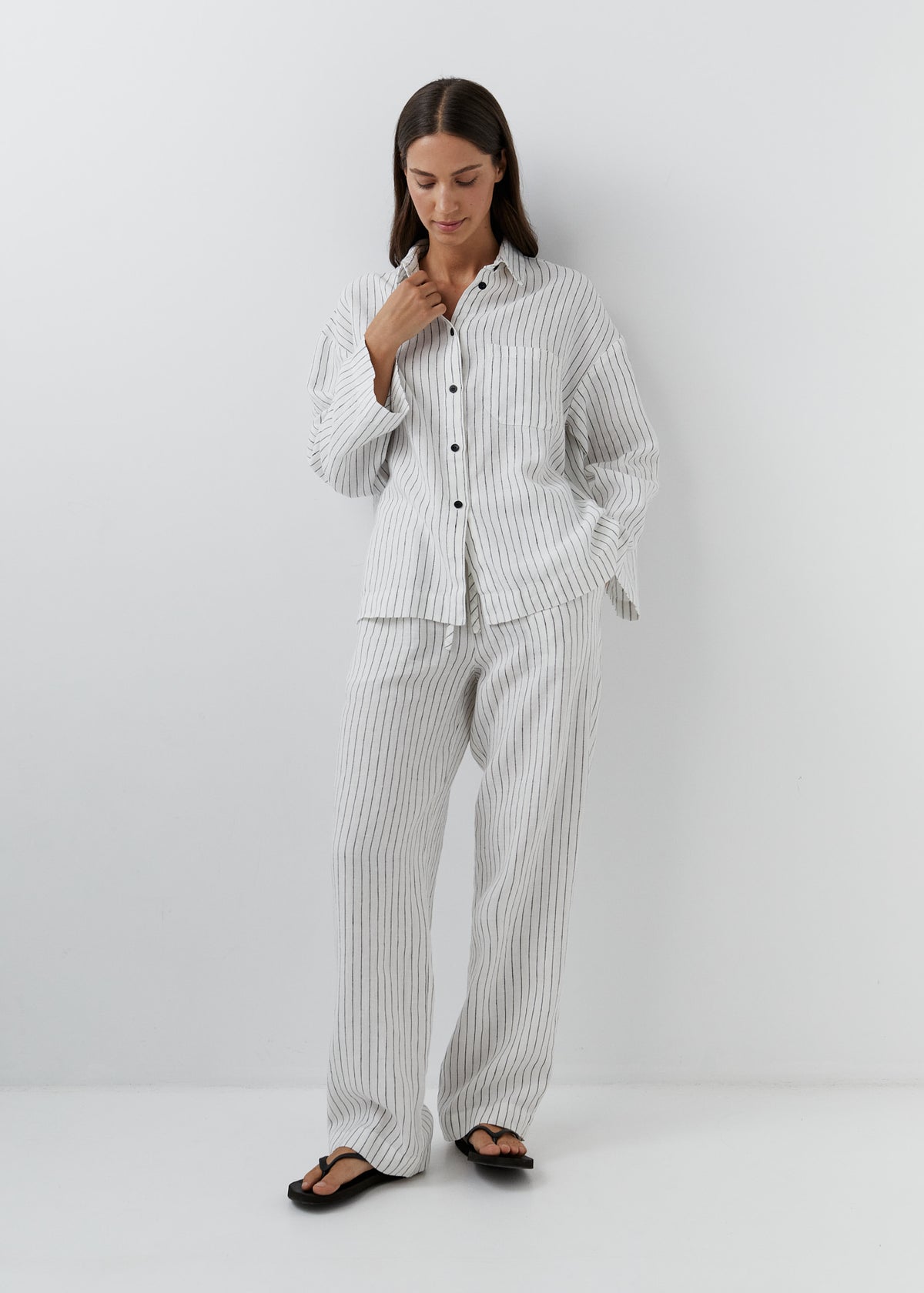Woman wearing black and white striped linen pants with a matching shirt.