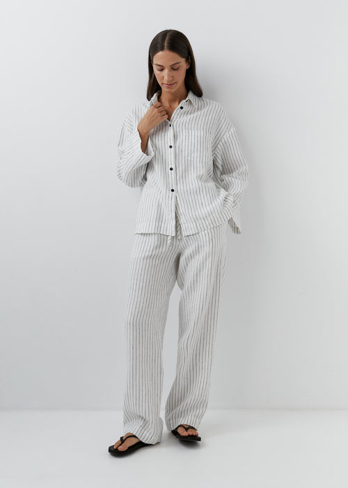 Woman wearing black and white striped linen pants with a matching shirt.