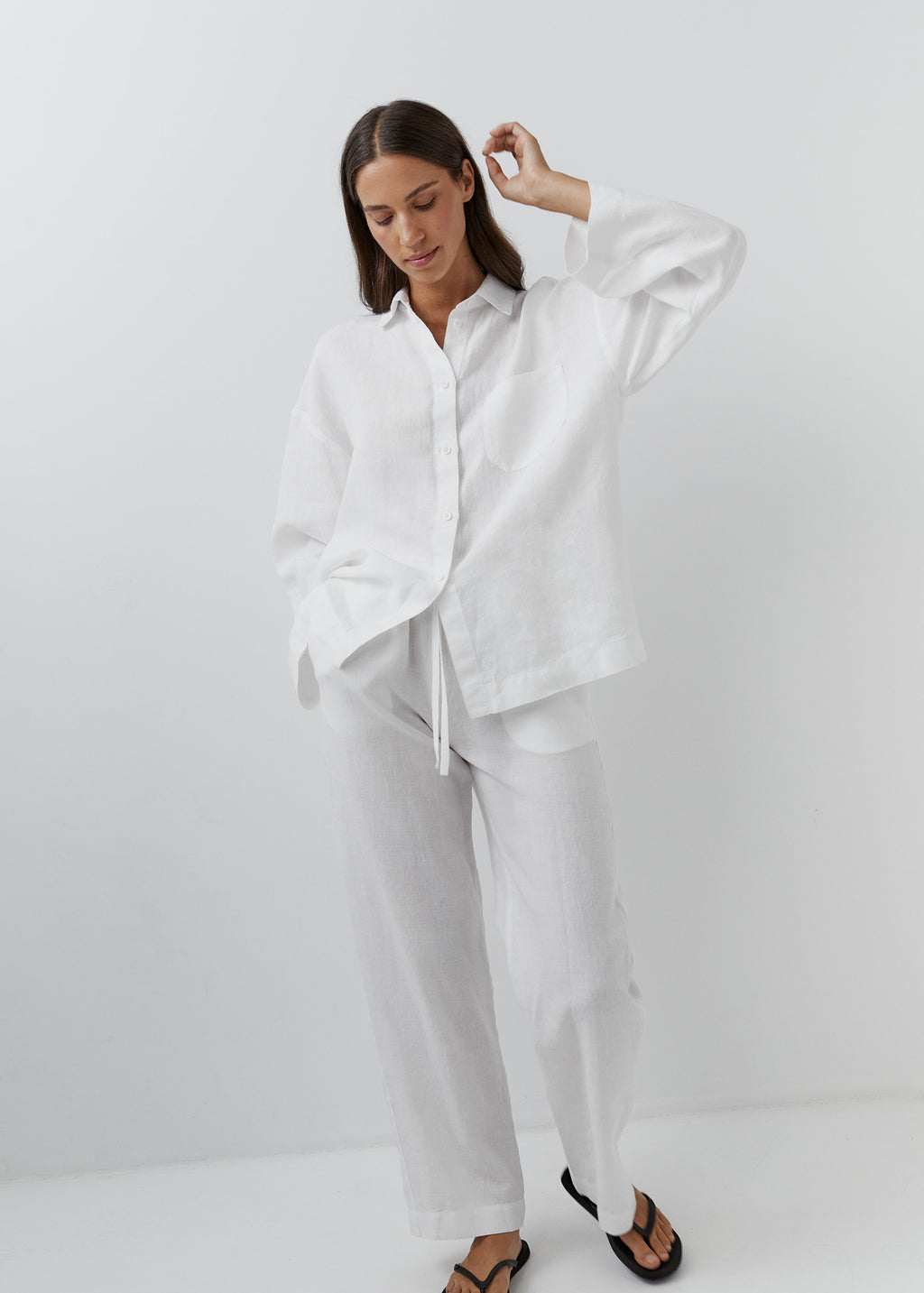 Woman wearing relaxed white trousers with a matching button-down linen shirt.