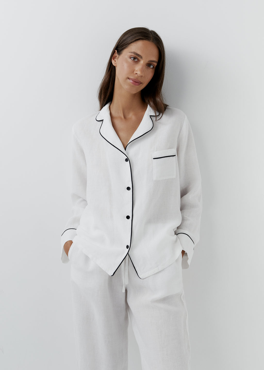 Women's white linen pyjamas with black piping trim, long-sleeve pajama shirt and matching pants, classic sleepwear.