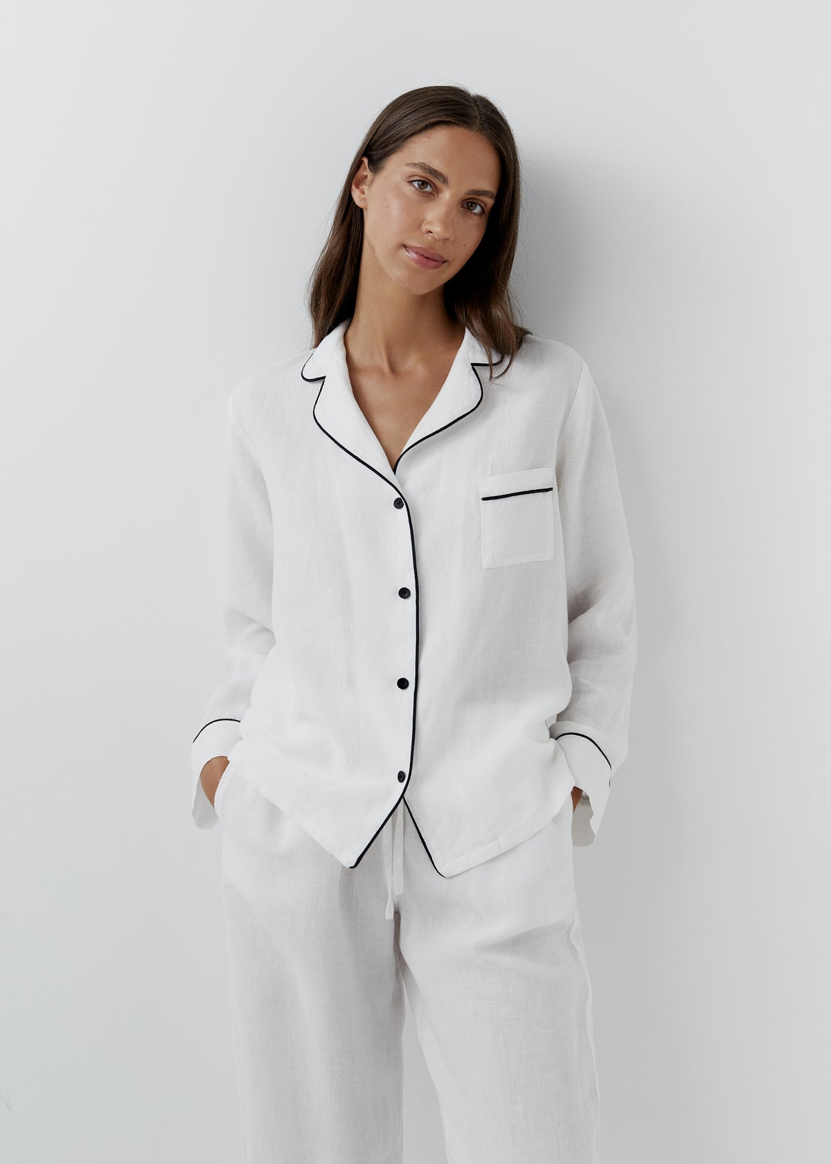 Women's white linen pyjamas with black piping trim, long-sleeve pajama shirt and matching pants, classic sleepwear.