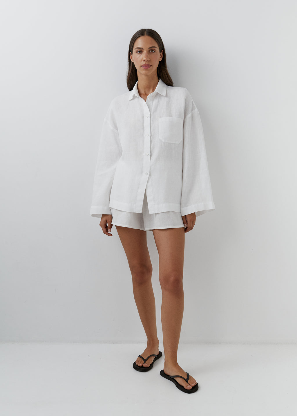 Woman wearing a relaxed white linen shirt with matching shorts. 