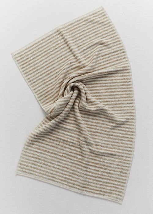 Beige and white striped linen towel folded on a light neutral background.