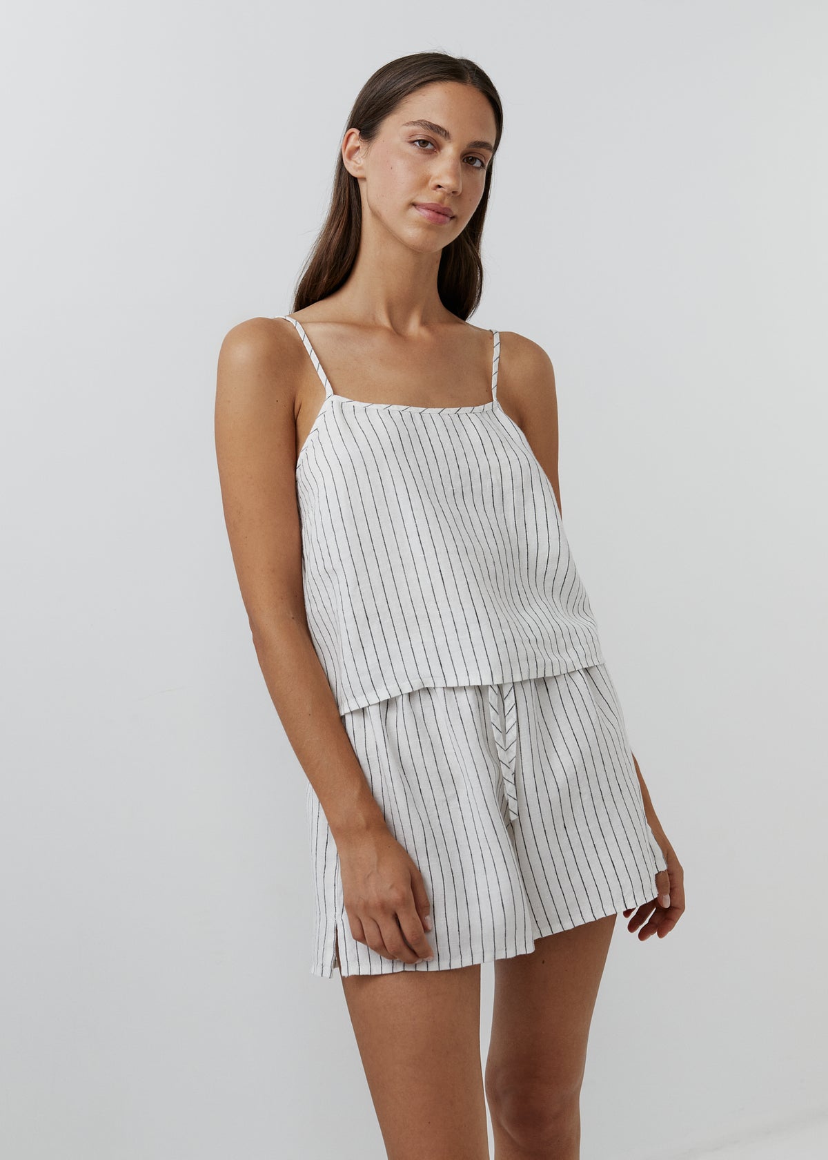 Woman wearing a white and black striped linen camisole set with matching shorts.