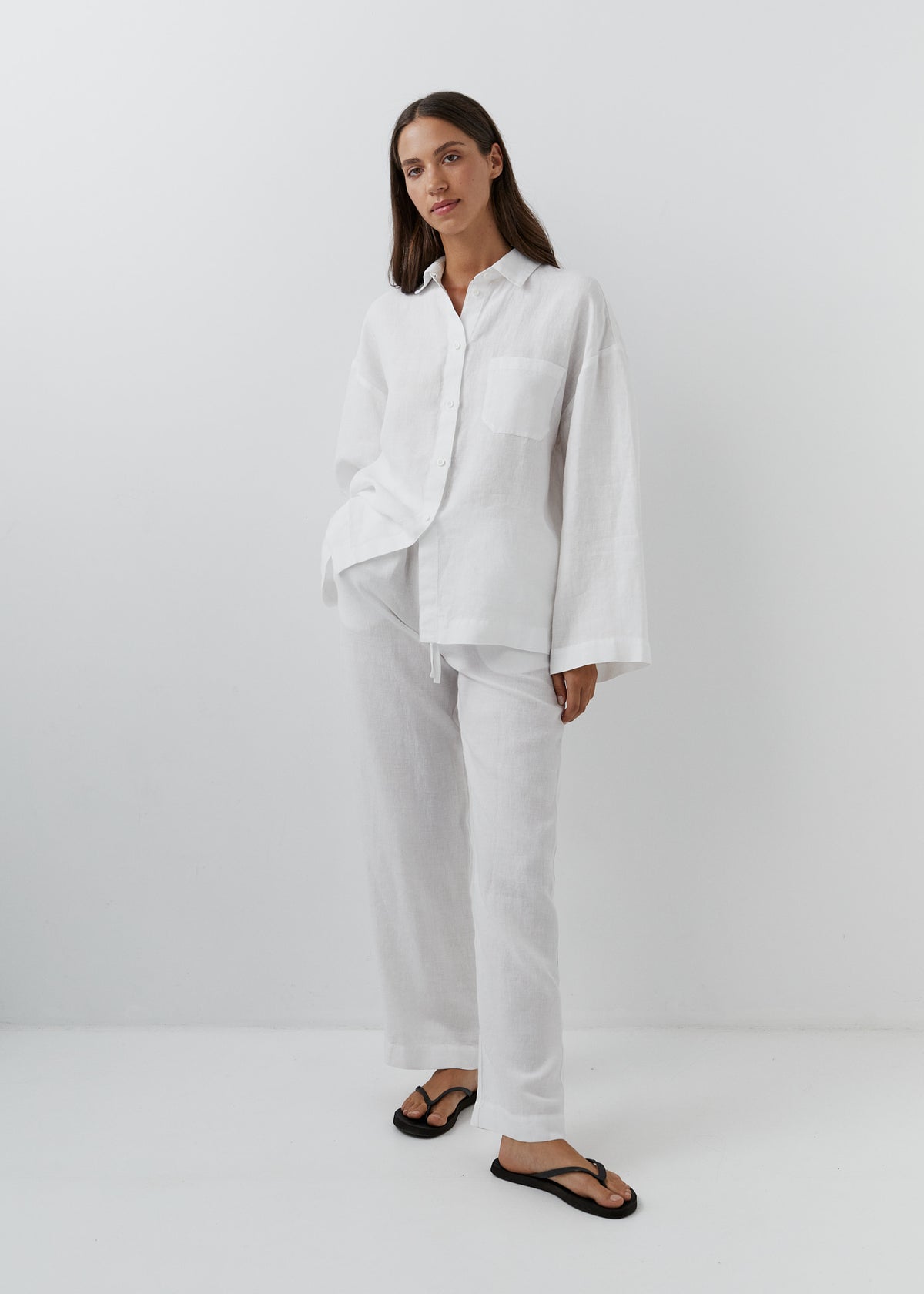 Woman wearing white linen pants with a matching white linen shirt.