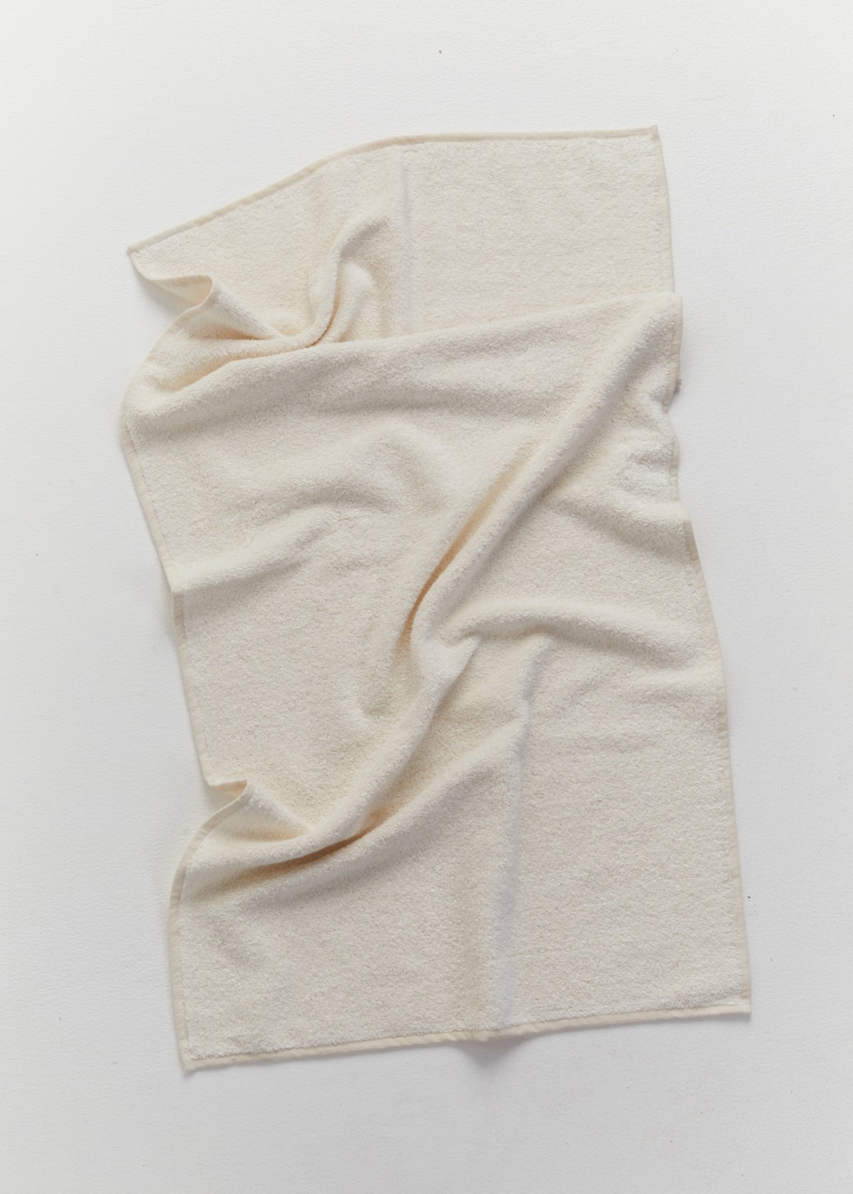 A folded ivory linen towel with a soft looped texture on a light neutral background.