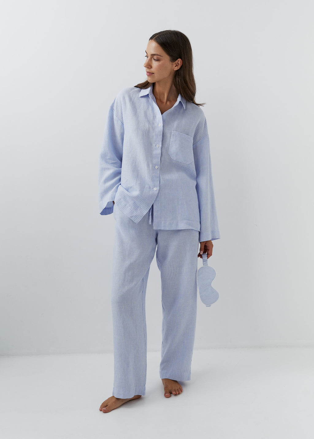 Woman wearing fine blue striped linen pants with a matching button-down shirt.
