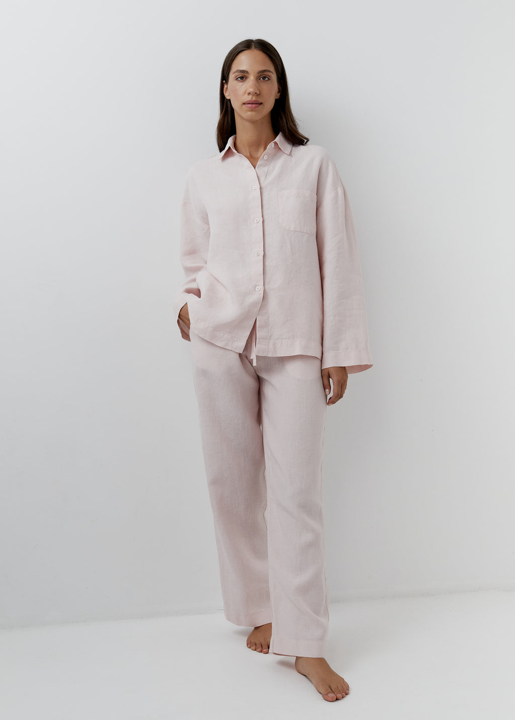 Woman wearing rose pink linen pants with a matching button-down linen shirt. 